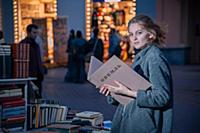 Девушка в сером пальто с книгой в руках на улице г
